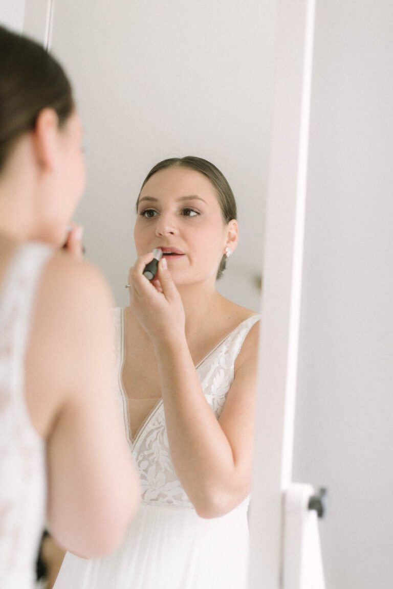 Die Braut beim auftragen des Lippenstift vor dem Spiegel