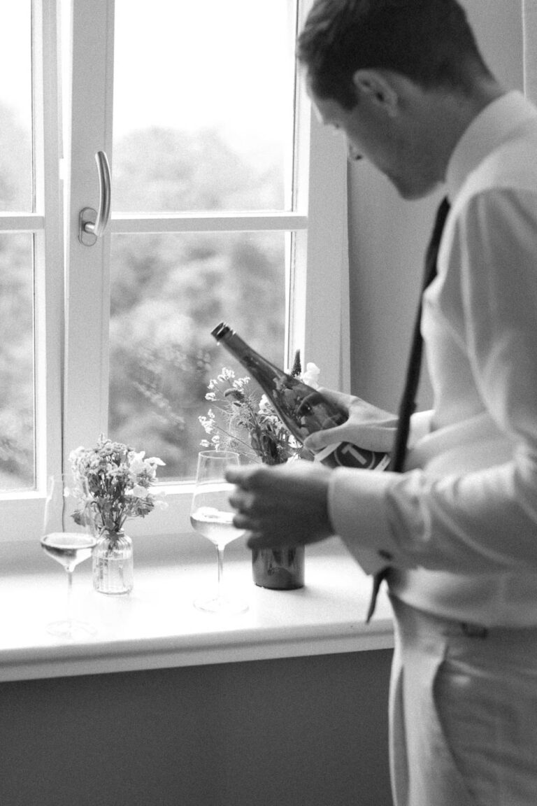 Der Trauzeuge vom Bräutigam schenkt Wein ein am Fenster im Sengerschloss am Tegernsee