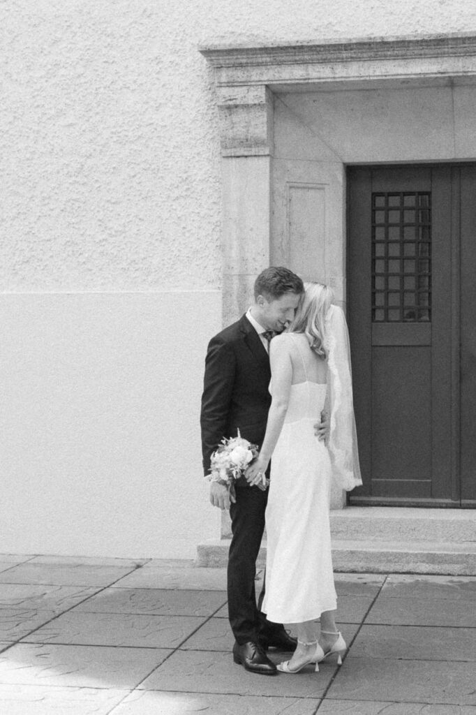 Der Bräutigam umarmt die Braut lächelnd, aufgenommen in Schwabing, Alexandra Kasper - Hochzeit Restaurant München