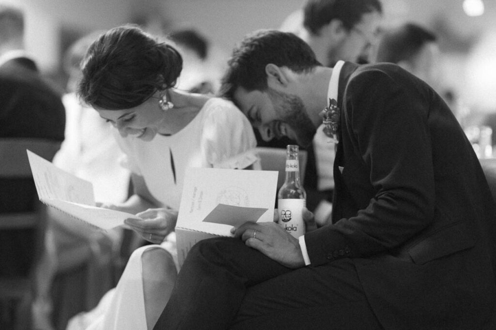 Braut und Bräutigam lachend während einer Rede von Gästen, Alexandra Kasper - Hochzeitsfotograf München