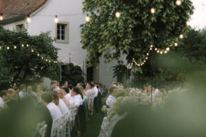 Die Hochzeitsgesellschaft sitzt an zwei langen Tafeln im Garten auf einem Weingut in der Pfalz